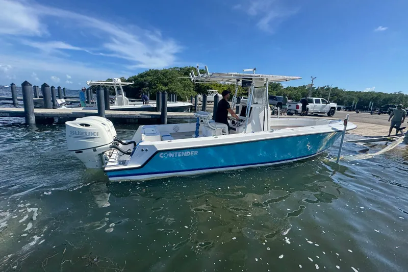 Slide: The Image of 2003 Contender 25 Open boat with Suzuki engine at dock, clear blue sky. - 26