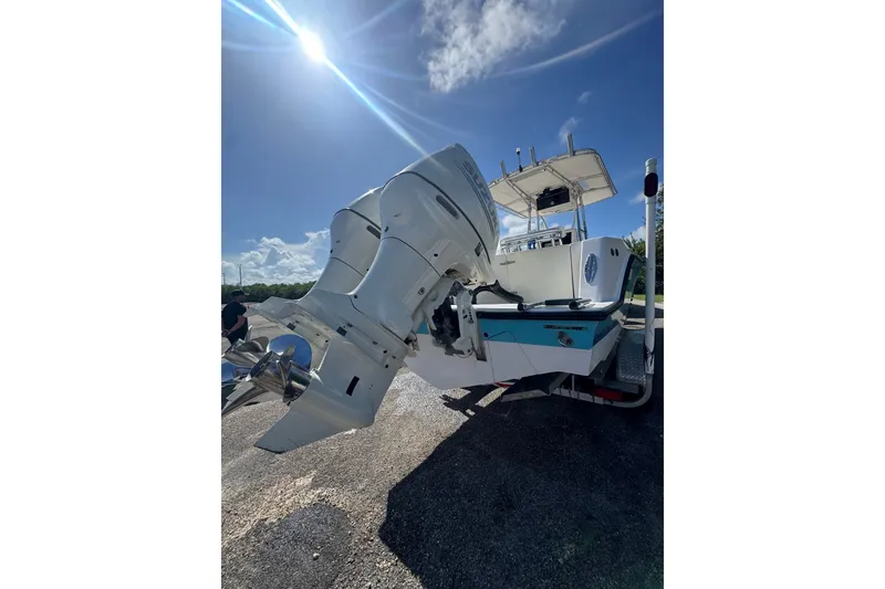 Slide: The Image of 2003 Contender 25 Open boat with dual outboard motors under a bright blue sky. - 34