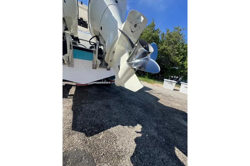 Slide: The Image of 2003 Contender 25 Open boat with dual outboard motors, parked on gravel under a clear blue sky. - 32