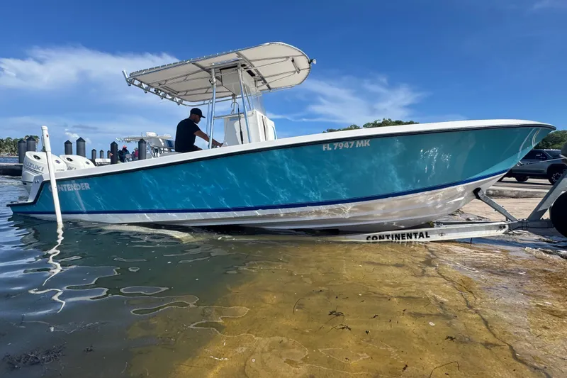 Slide: The Image of 2003 Contender 25 Open boat on trailer, blue hull, dockside with clear sky background. - 20