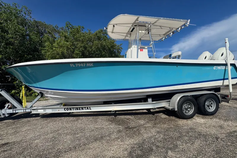 Slide: The Image of 2003 Contender 25 Open boat on trailer, vibrant blue hull, parked outdoors. - 0