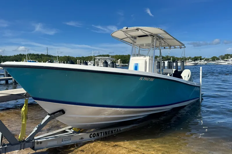 The Image of 2003 Contender 25 Open boat on trailer by the water, clear blue sky. - 16