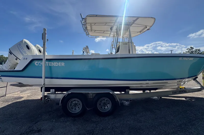 Slide: The Image of 2003 Contender 25 Open boat on trailer, featuring dual Suzuki engines, under a clear blue sky. - 12