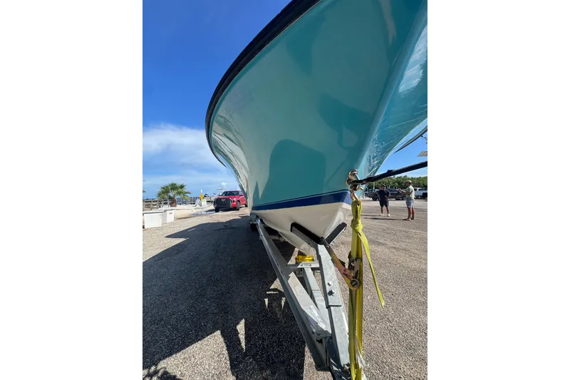 Slide: The Image of 2003 Contender 25 Open boat on trailer, sunny day, blue sky background. - 17