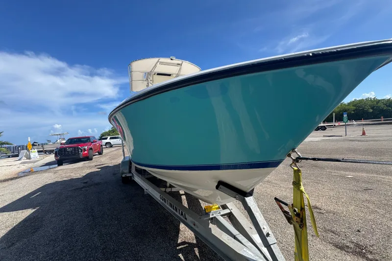 Slide: The Image of 2003 Contender 25 Open boat on trailer, vibrant blue hull, sunny day, parked near vehicles. - 7