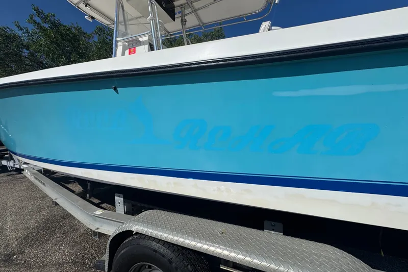 Slide: The Image of 2003 Contender 25 Open boat on trailer, featuring a blue hull with faded lettering. - 15