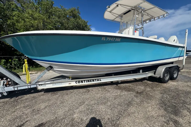 Slide: The Image of 2003 Contender 25 Open boat on trailer, blue hull, sunny day, parked outdoors. - 1