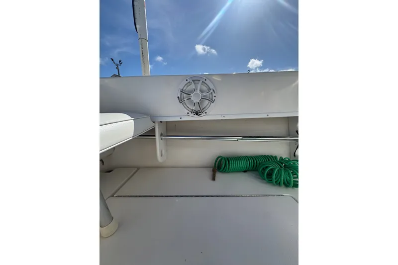 Slide: The Image of 2003 Contender 25 Open boat interior with speaker and coiled green hose under sunny sky. - 39
