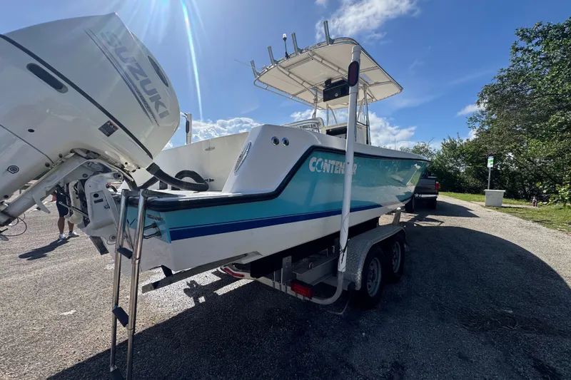 Slide: The Image of 2003 Contender 25 Open boat on trailer, featuring Suzuki outboard motor, under clear blue sky. - 14
