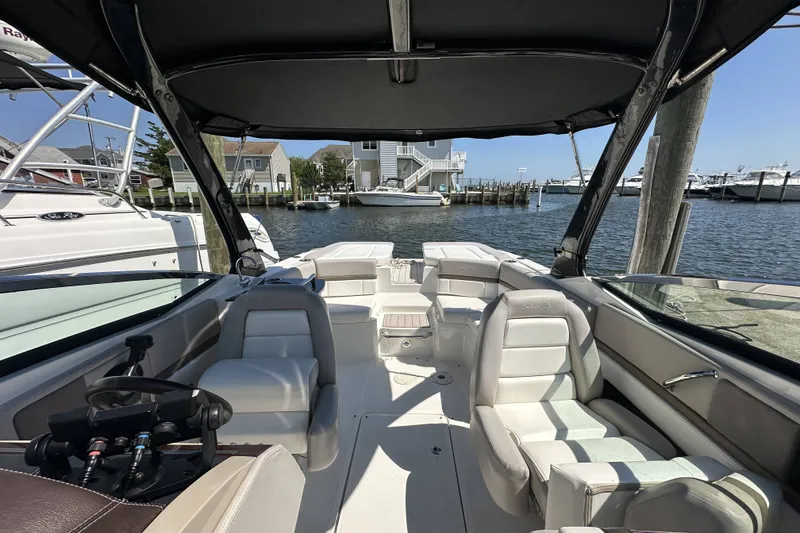 Slide: The Image of 2012 Sea Ray SLX 250 boat interior with seating, docked by waterfront homes. - 3
