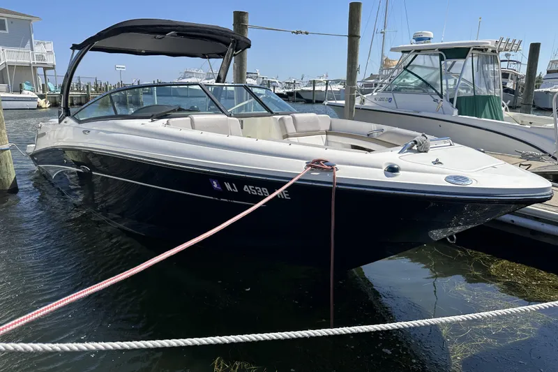 The Image of 2012 Sea Ray SLX 250 boat docked at a marina, featuring sleek design and black hull. - 0