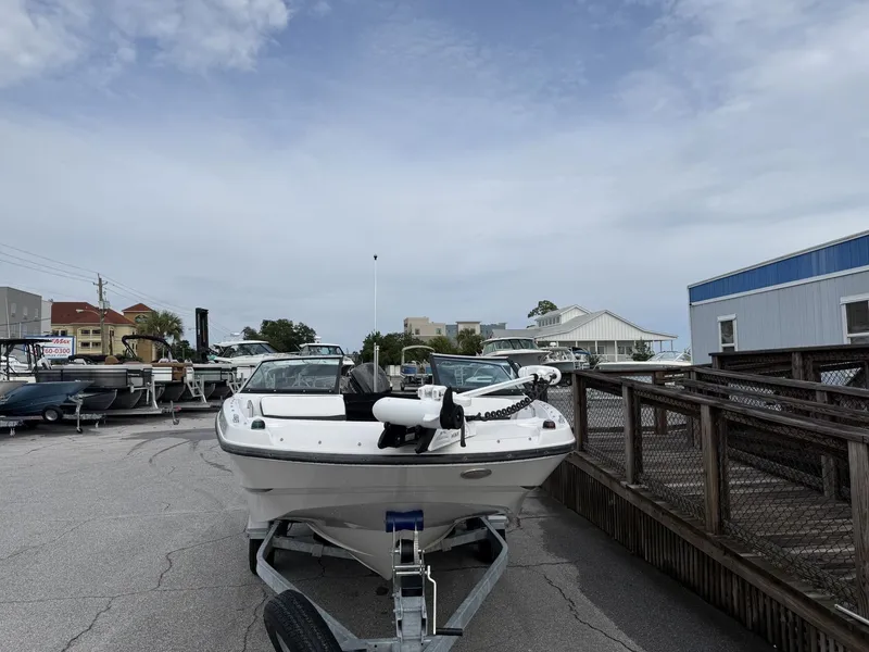 Slide: The Image of A 2019 Four Winns HD 200 Freedom on a trailer, parked in a marina area. - 2