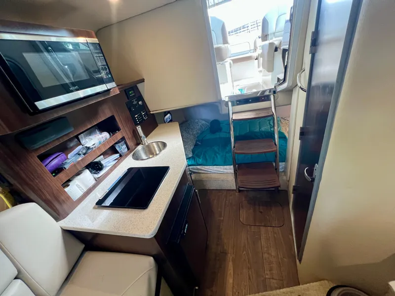 Slide: The Image of Interior of a 2017 Regal 26 Express with a kitchenette, bed, and stairs to the upper deck. - 17