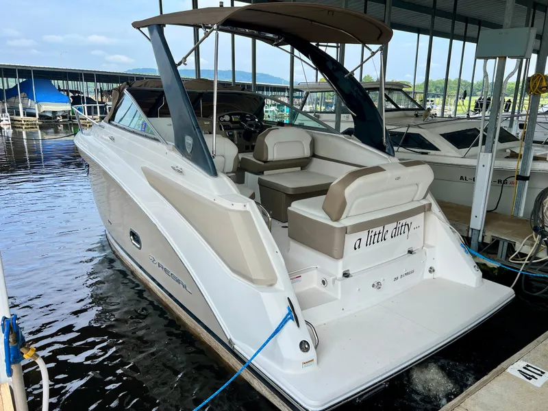 Slide: The Image of A 2017 Regal 26 Express boat docked in a covered marina. It features a beige and white color scheme. - 2