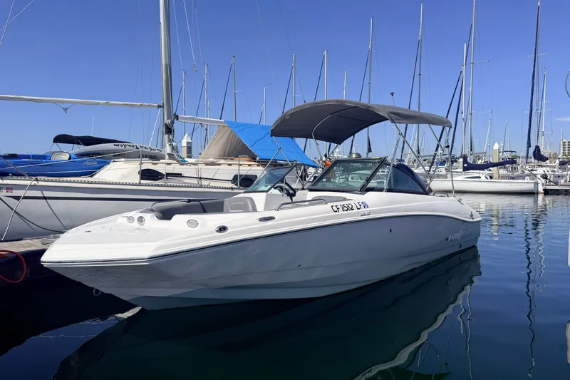 The Image of 2026 NauticStar 203 DC Deck boat docked in a marina, surrounded by sailboats. - 0