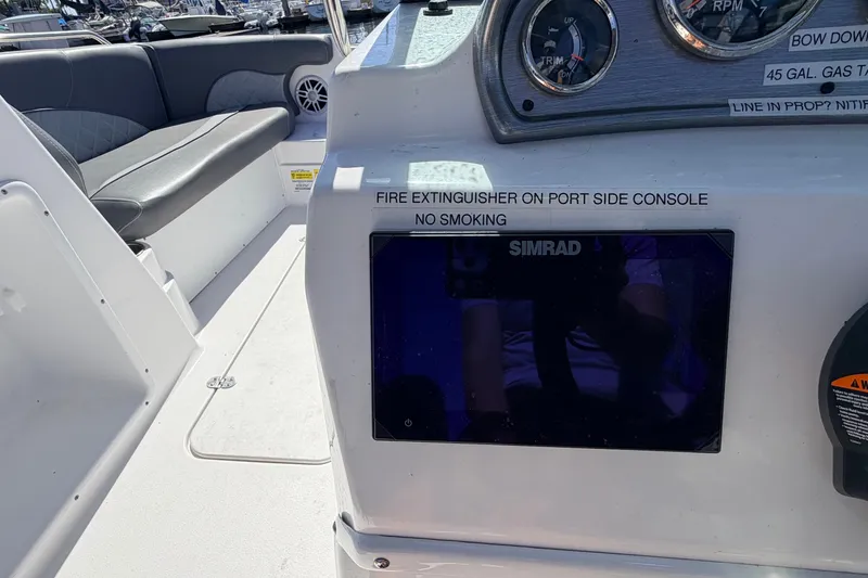 Slide: The Image of 2026 NauticStar 203 DC Deck boat dashboard with Simrad display and safety instructions. - 16