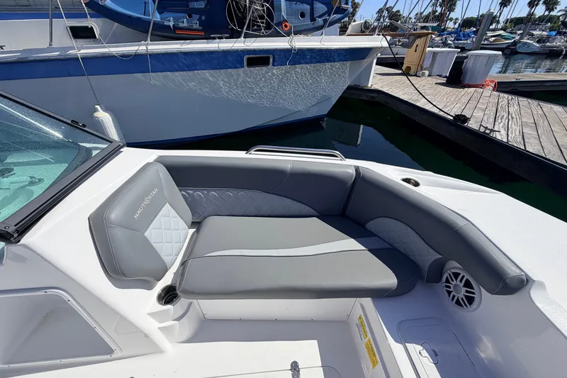 Slide: The Image of 2026 NauticStar 203 DC Deck boat interior with gray seating at marina. - 22