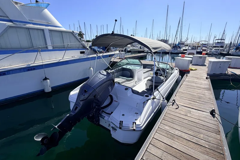 Slide: The Image of 2026 NauticStar 203 DC Deck boat docked at marina with outboard motor and canopy. - 3