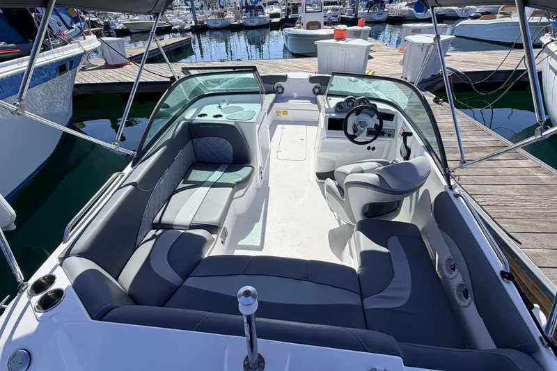 Slide: The Image of 2026 NauticStar 203 DC Deck boat interior at marina, featuring seating and steering console. - 5
