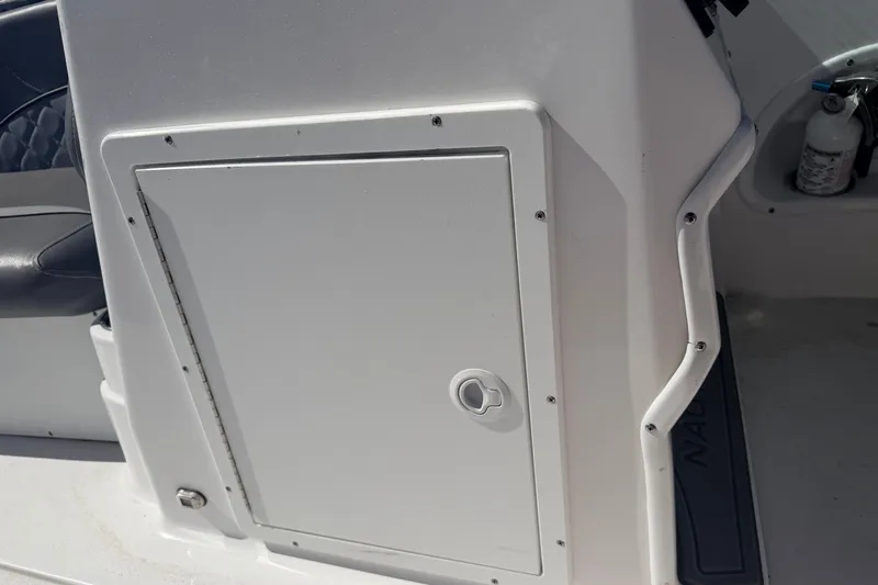 Slide: The Image of 2026 NauticStar 203 DC Deck boat interior with storage compartment and fire extinguisher. - 18