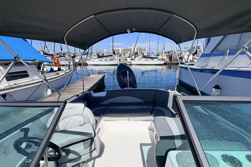 Slide: The Image of 2026 NauticStar 203 DC Deck boat docked at marina with canopy and seating. - 7