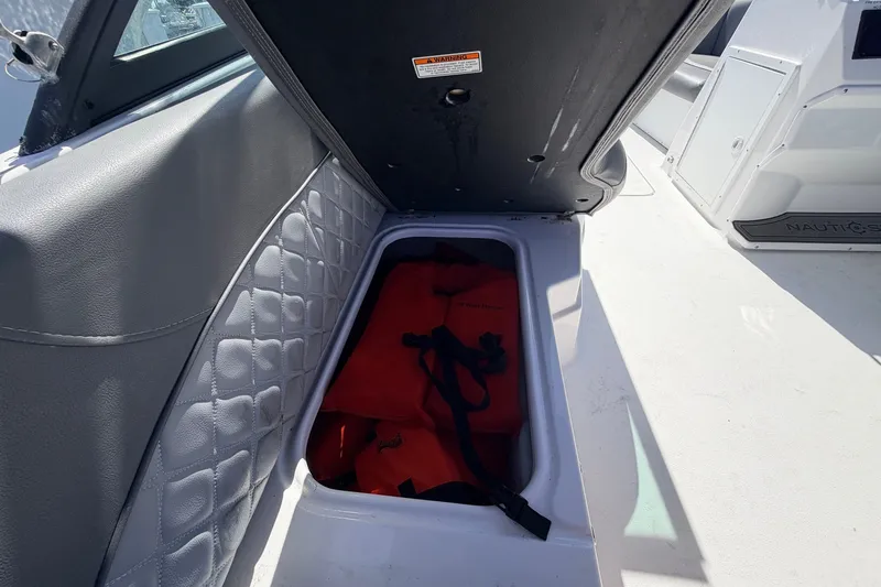 Slide: The Image of Storage compartment with life jackets on a 2026 NauticStar 203 DC Deck boat. - 23