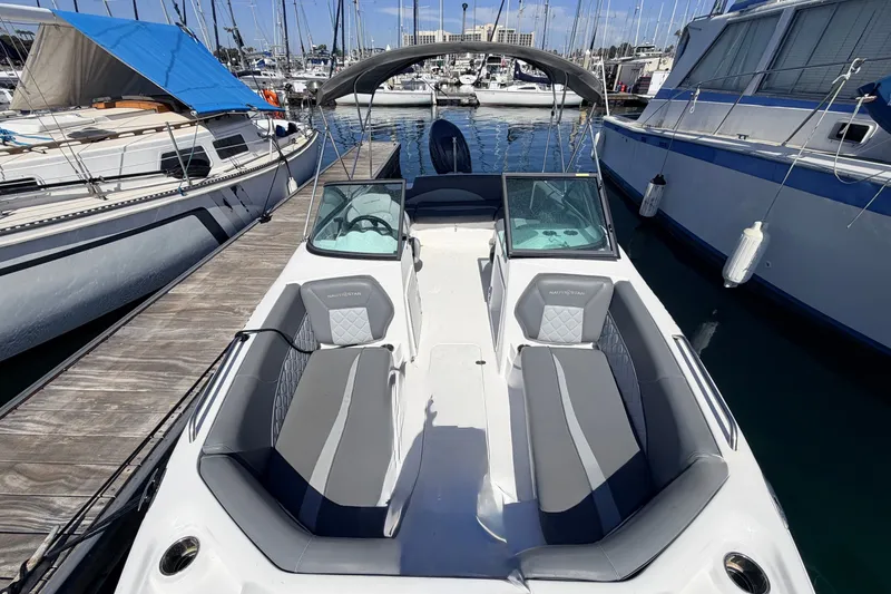 Slide: The Image of 2026 NauticStar 203 DC Deck boat docked at marina, featuring sleek seating and modern design. - 25