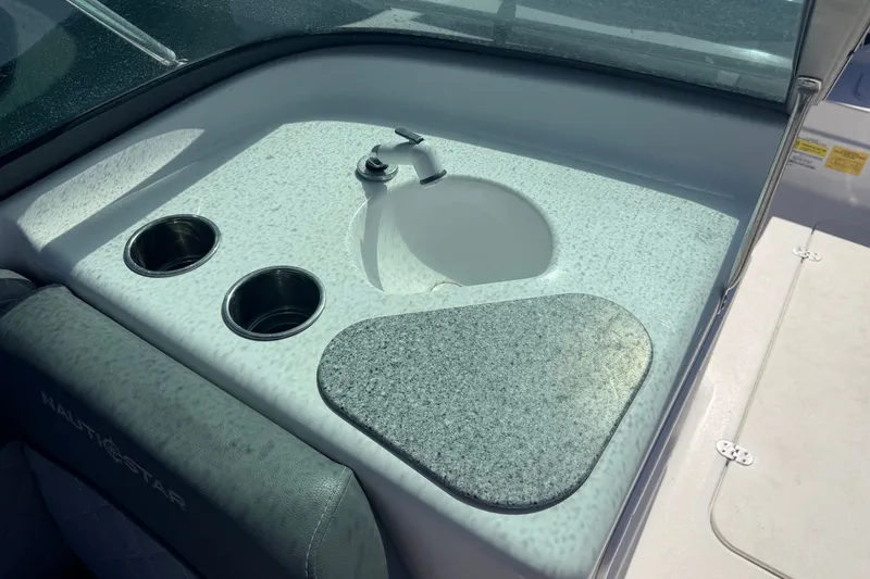 Slide: The Image of 2026 NauticStar 203 DC Deck boat interior with sink and cup holders. - 17