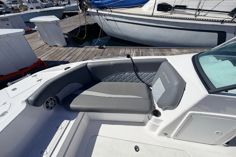 Slide: The Image of 2026 NauticStar 203 DC Deck boat interior with gray seating at marina. - 21