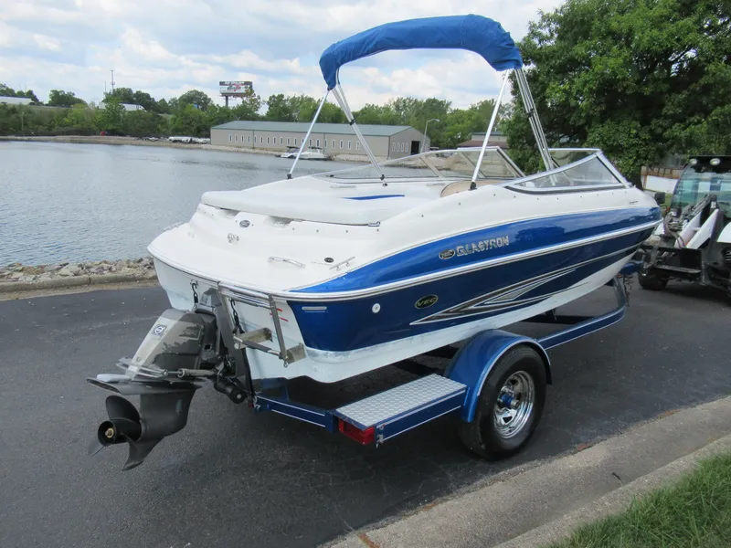 Slide: The Image of 2008 Glastron GXL 185 boat with blue and white exterior on a trailer by the water. - 1