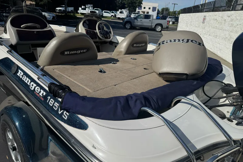 Slide: The Image of 2004 Ranger 185 VS boat interior with seats and steering wheel, parked outdoors. - 26
