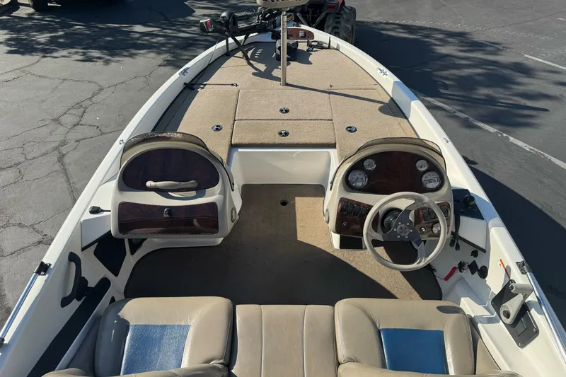 Slide: The Image of 2004 Ranger 185 VS boat interior with steering wheel and seating, parked on pavement. - 7