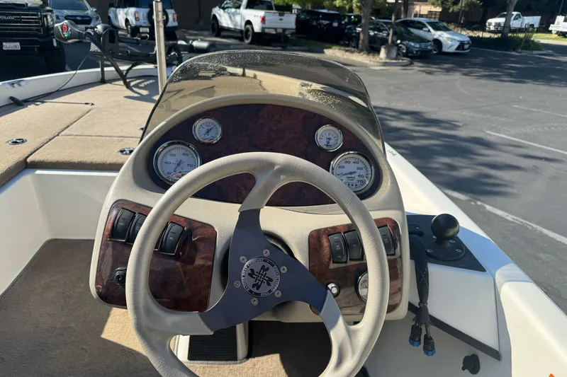 Slide: The Image of 2004 Ranger 185 VS boat dashboard with steering wheel and gauges in a parking lot. - 12