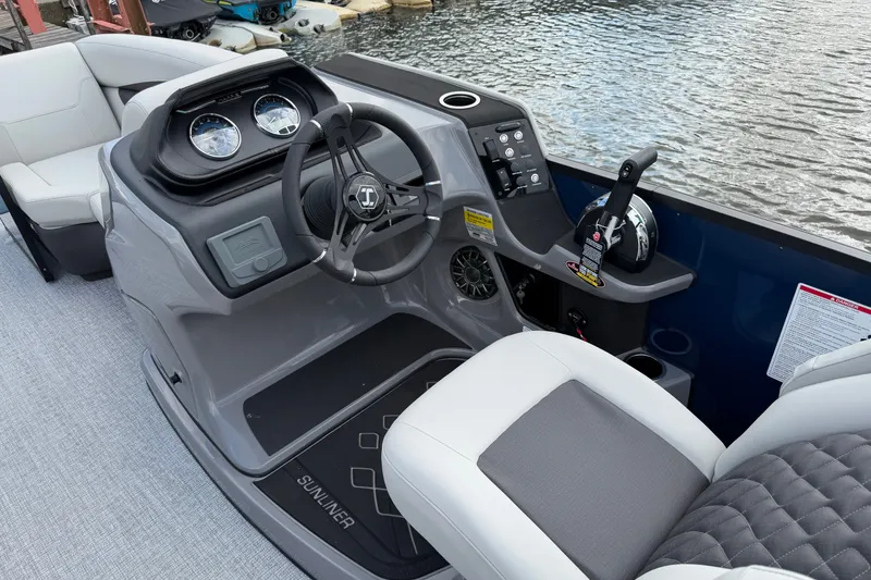 Slide: The Image of 2027 Harris Sunliner 210 boat dashboard with steering wheel and controls by the water. - 8