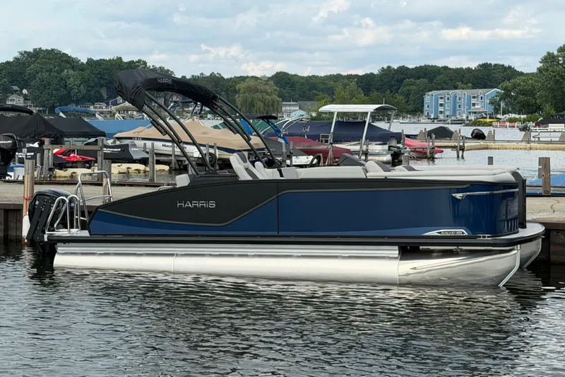 The Image of 2027 Harris Sunliner 210 pontoon boat docked at a marina, featuring sleek design and modern amenities. - 0