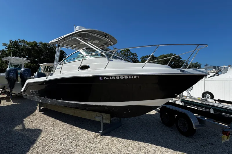 The Image of 2010 Robalo R265 Walkaround boat on trailer, parked outdoors under clear blue sky. - 0