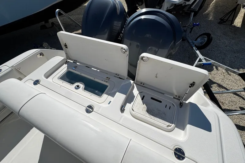 Slide: The Image of 2010 Robalo R265 Walkaround boat with open storage compartments and dual outboard motors. - 13