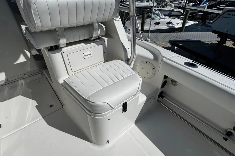 Slide: The Image of 2010 Robalo R265 Walkaround boat interior with white cushioned seating and storage compartment. - 19