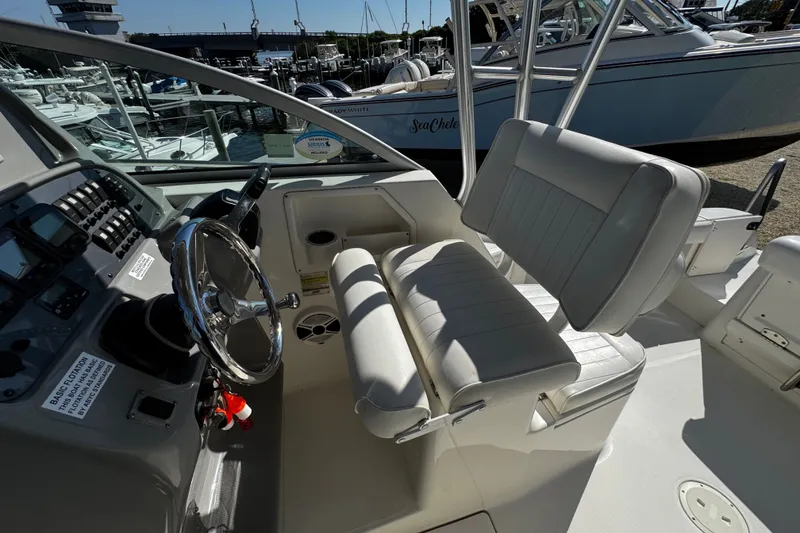 Slide: The Image of 2010 Robalo R265 Walkaround boat interior with steering wheel and seating at marina. - 22