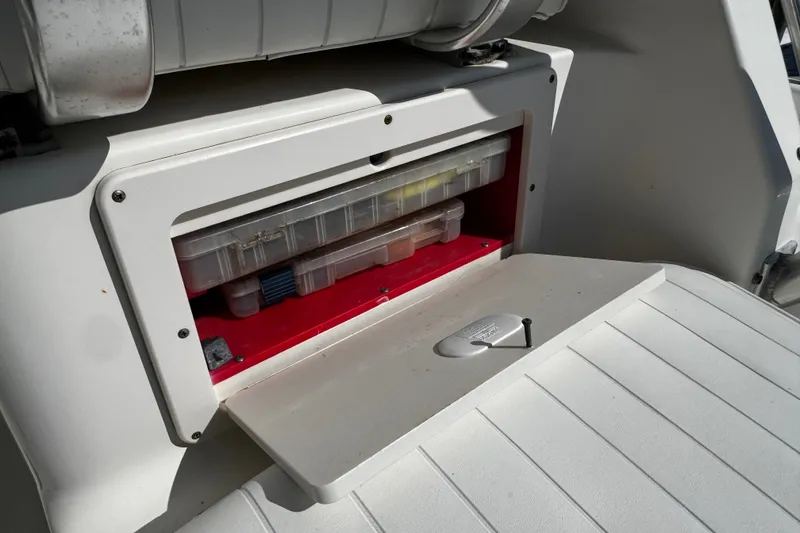 Slide: The Image of Storage compartment on a 2010 Robalo R265 Walkaround boat, containing tackle boxes. - 21