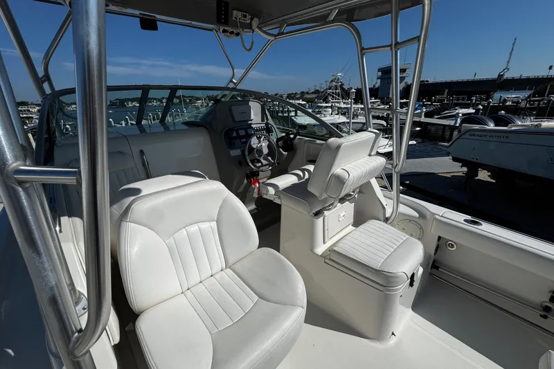 Slide: The Image of 2010 Robalo R265 Walkaround boat interior with white seating and control panel at marina. - 10