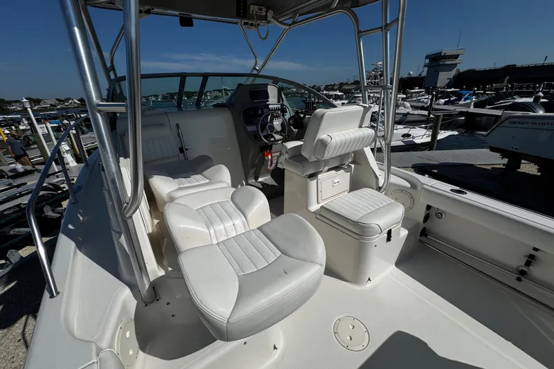 Slide: The Image of 2010 Robalo R265 Walkaround boat interior with white seating and steering console at marina. - 40