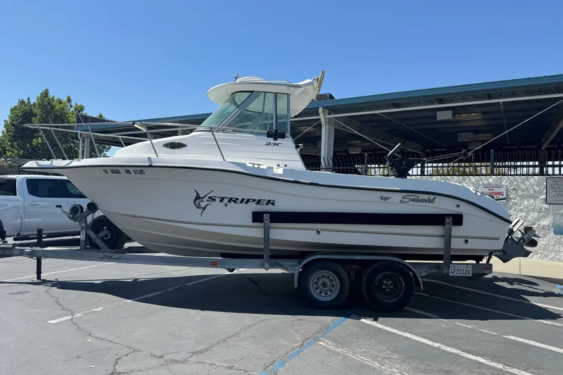 The Image of 2005 Seaswirl Striper 2301 Walkaround I/O boat on trailer in parking lot. - 1