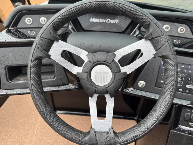 Slide: The Image of The image shows the steering wheel of a MasterCraft NXT23 boat. It is modern and wet. - 34