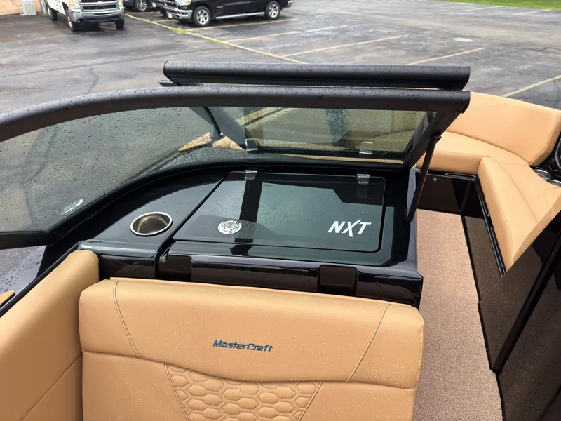 Slide: The Image of The image shows the interior of a 2027 MasterCraft NXT23 boat with beige seats and a black dashboard. - 27