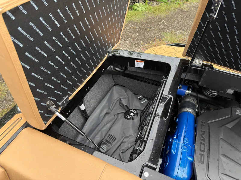Slide: The Image of The storage compartment of a 2027 MasterCraft NXT23 with a blue engine and cover. - 12