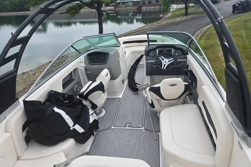 Slide: The Image of 2017 Chaparral 246 SSi boat interior with seating and steering wheel, docked by a calm lake. - 10
