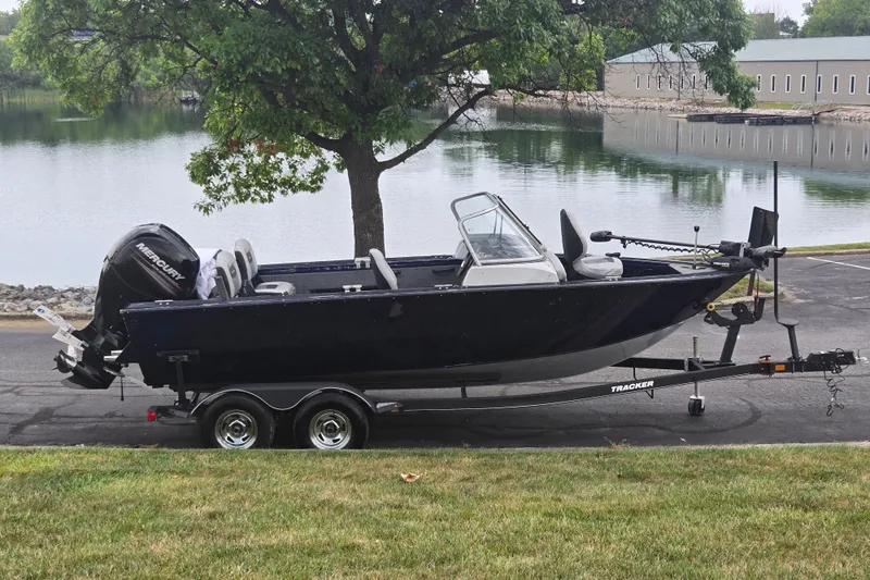 The Image of 2019 Tracker Targa V-18 Combo boat on trailer by a serene lake. - 0