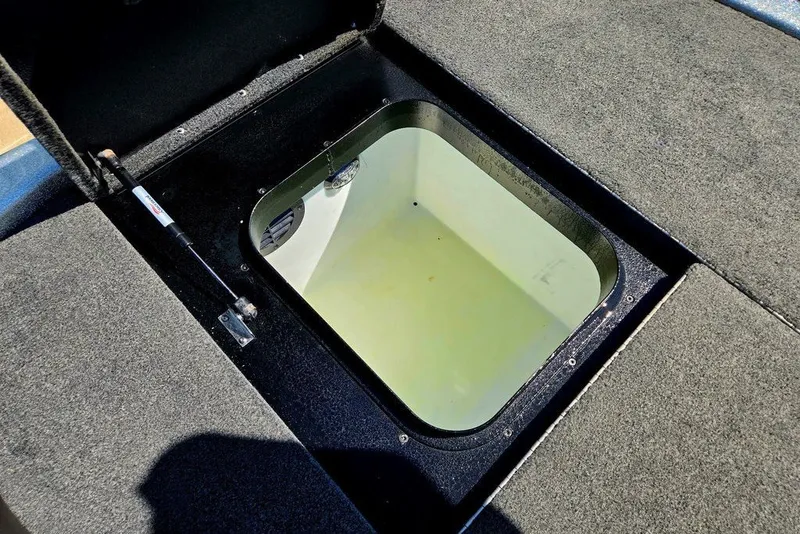 Slide: The Image of Open storage compartment in 2026 Skeeter ZXR21 boat, featuring carpeted interior and hydraulic lift. - 33