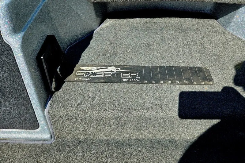 Slide: The Image of Interior of 2026 Skeeter ZXR21 boat with ProRule measuring tool on carpeted floor. - 9